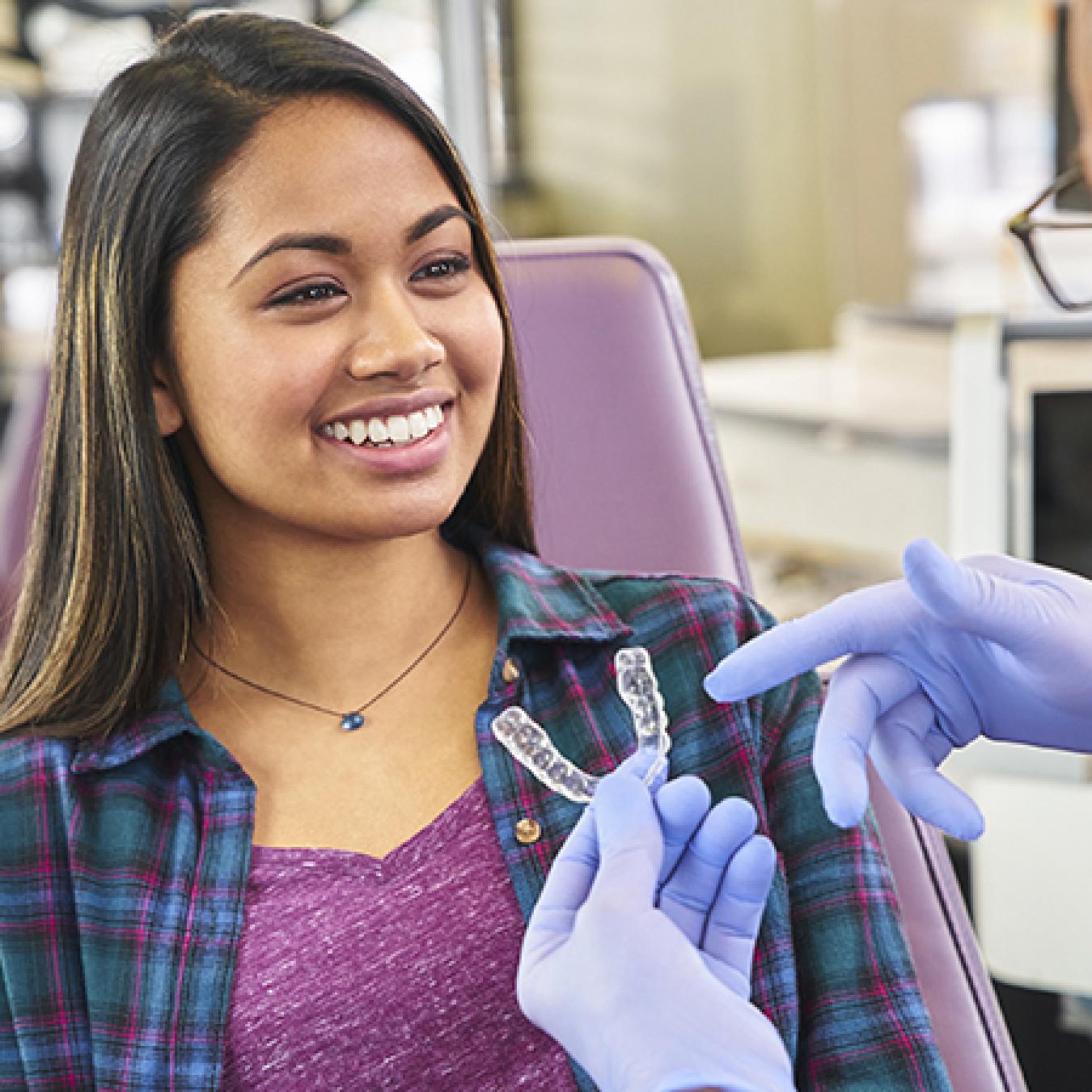 A woman smiling while a orthodontist shows her clear aligners